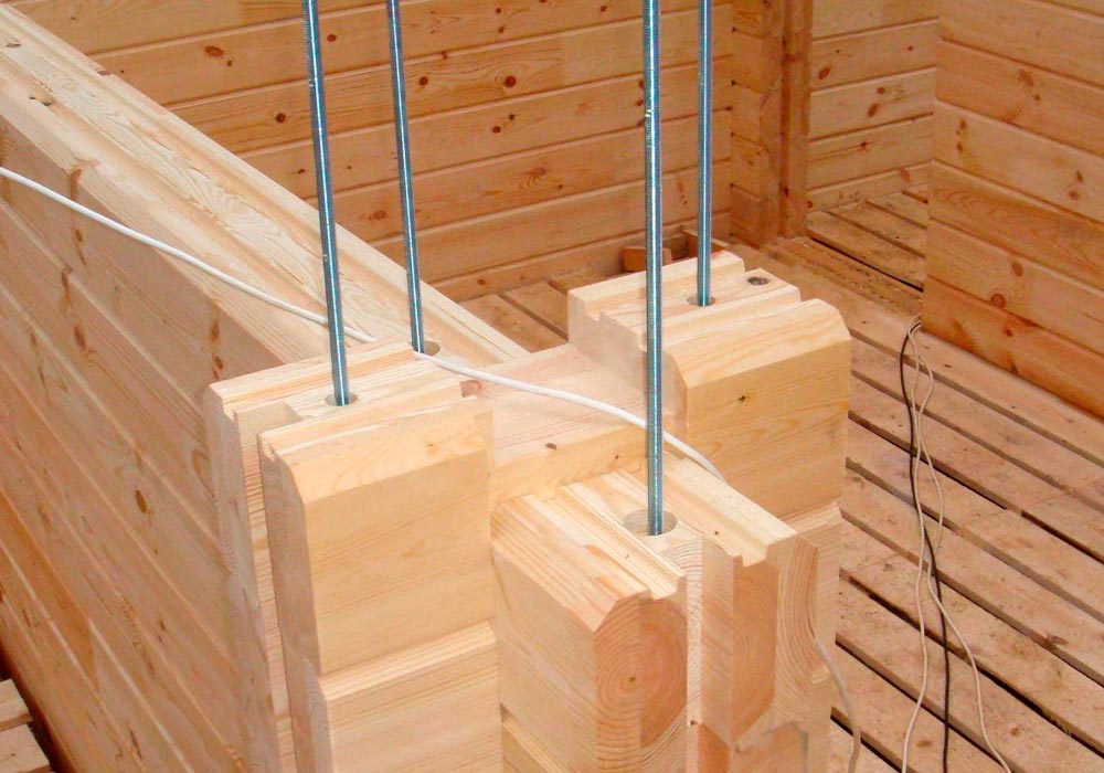 Gewindestangen zur Stabilisierung einer Holzkonstruktion – vertikale Gewindestäbe in einem Holzhaus aus Massivholz